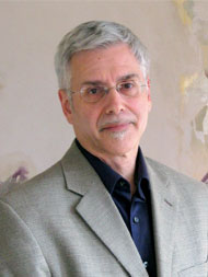 A man with grey hair and glasses wearing a suit.