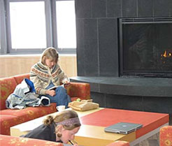Two women sitting on a couch in front of a fireplace.