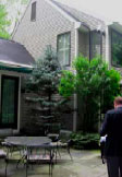 A man in suit and tie standing outside of a house.